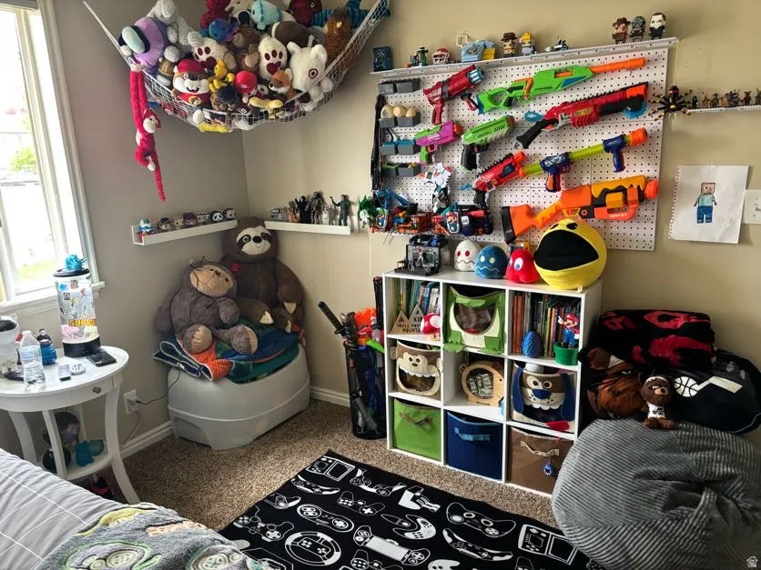 Carpeted bedroom featuring a window with white trim, a white corner shelving unit, and a white pegboard wall