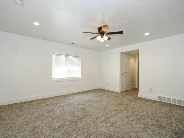 Spacious interior room featuring neutral-toned carpet, white walls, and recessed lighting