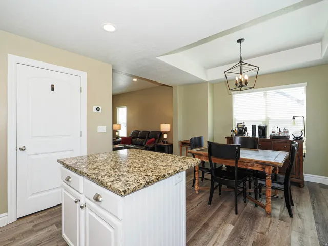 Kitchen island with granite countertop, white cabinetry, and wood-finish flooring