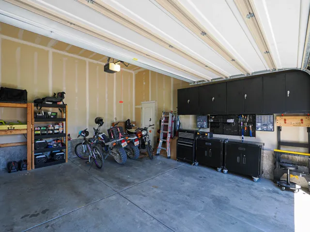 Spacious garage featuring a concrete floor, overhead door, and exposed wall studs