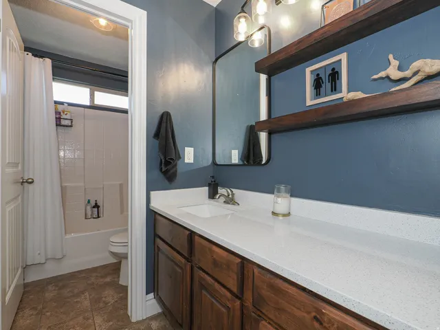Bathroom featuring a single vanity with wood cabinetry, a white countertop, and an undermount sink