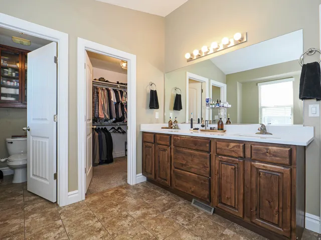 Bathroom featuring a dual vanity with wood cabinetry, a white countertop, and individual sinks