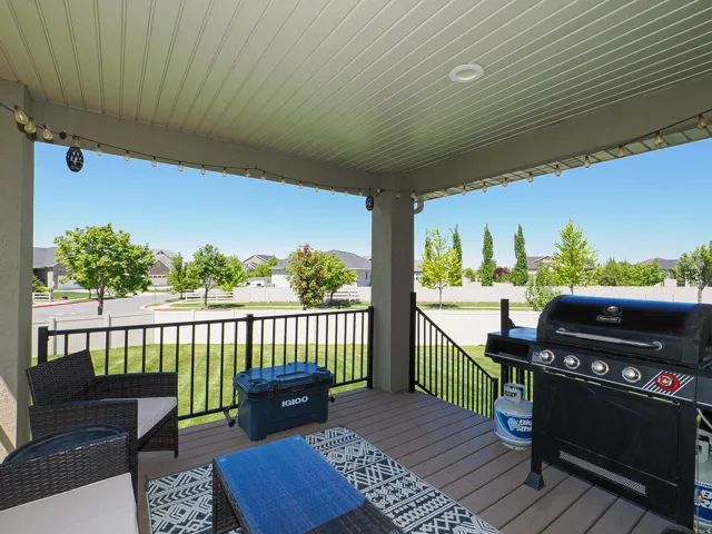 Covered outdoor deck with composite decking, black metal railings, recessed lighting, and string lights