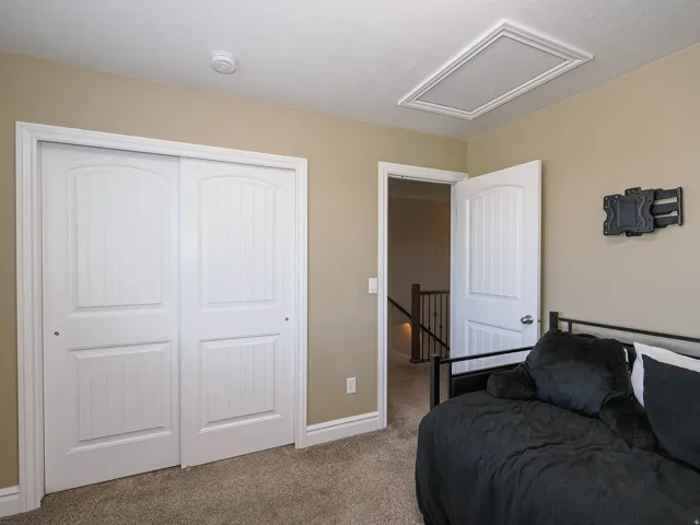 Carpeted room featuring a white bi-fold closet with arched paneling, a white door frame, and a white ceiling with an access panel