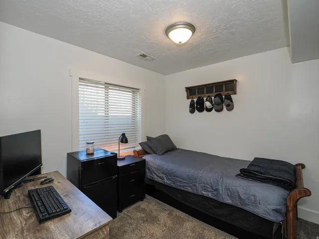 Room featuring a window with blinds, wood-finish desk, and a semi-flush mount ceiling light