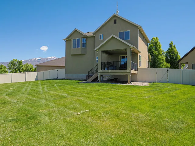 Expansive backyard featuring a large lawn, a covered patio, and a privacy fence