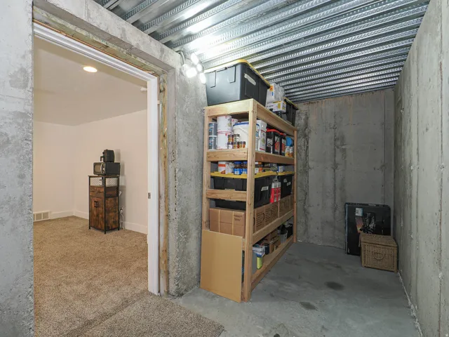 Exposed concrete walls and flooring in a utility space with metal ceiling decking and overhead task lighting