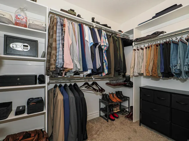Walk-in closet featuring built-in shelving, multiple hanging rods, and integrated drawer storage