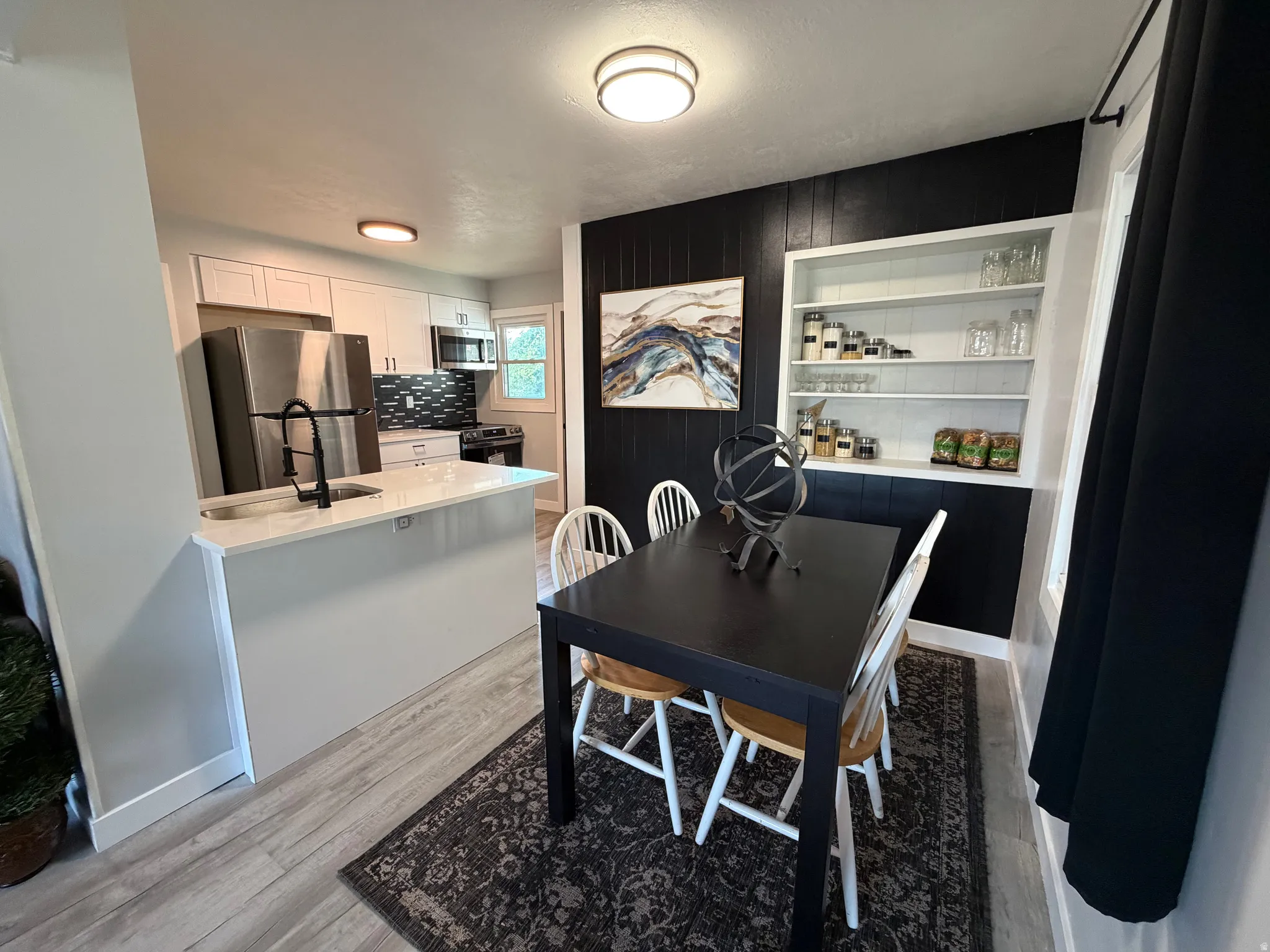Kitchen featuring a peninsula with a sink and matte black faucet, stainless steel appliances, and a tiled backsplash