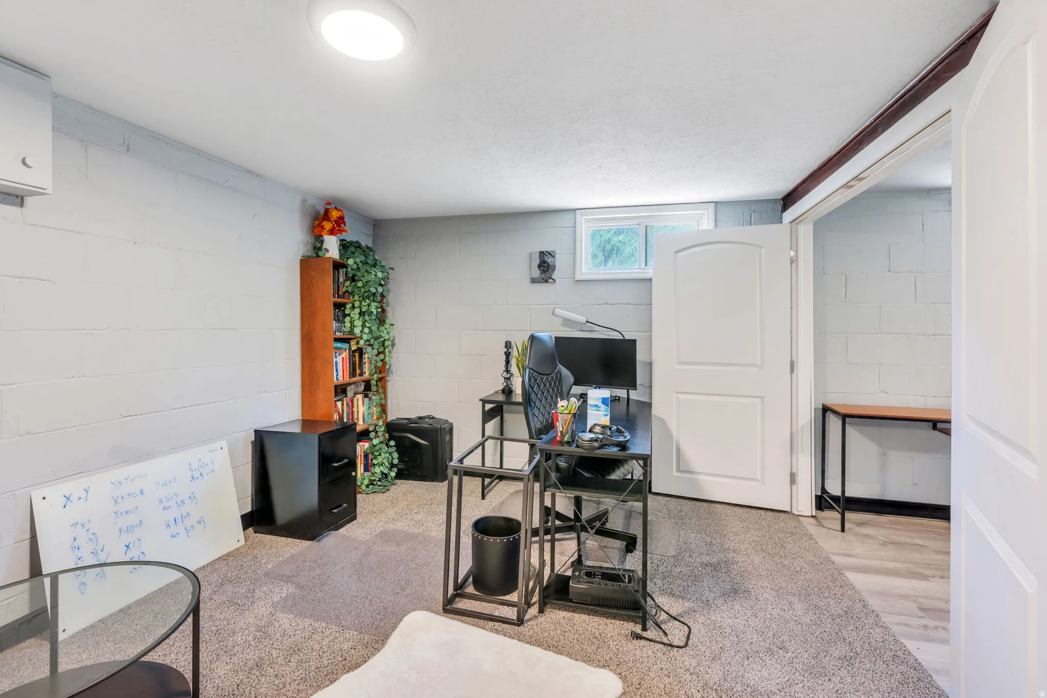 Versatile interior space featuring light gray painted block walls, a flush-mount ceiling light, and a window providing natural illumination