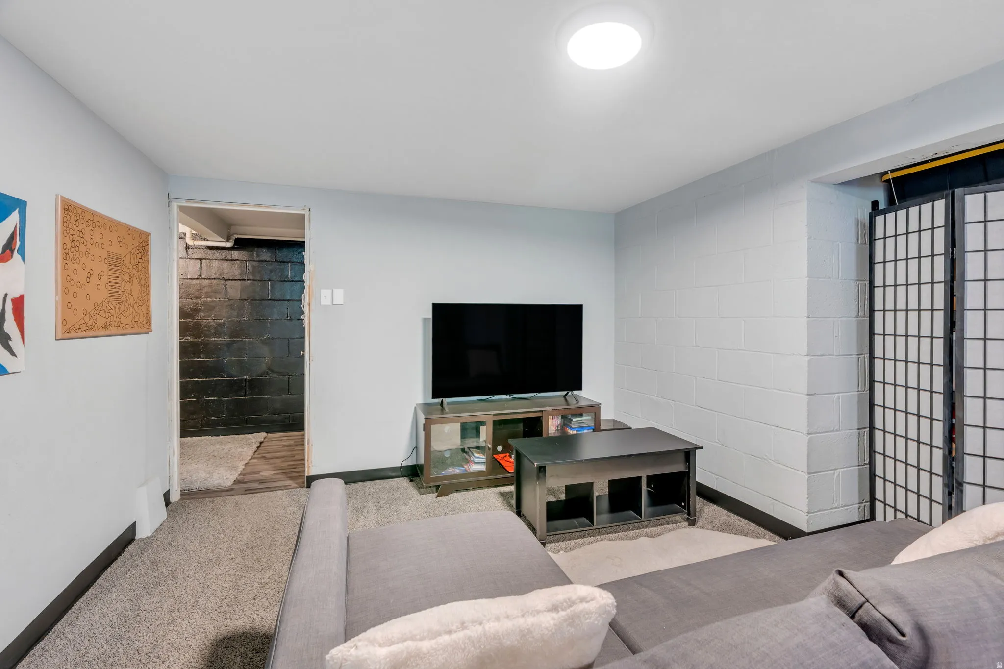 Carpeted recreational space with light gray walls, a flush-mount ceiling light, and a black baseboard trim