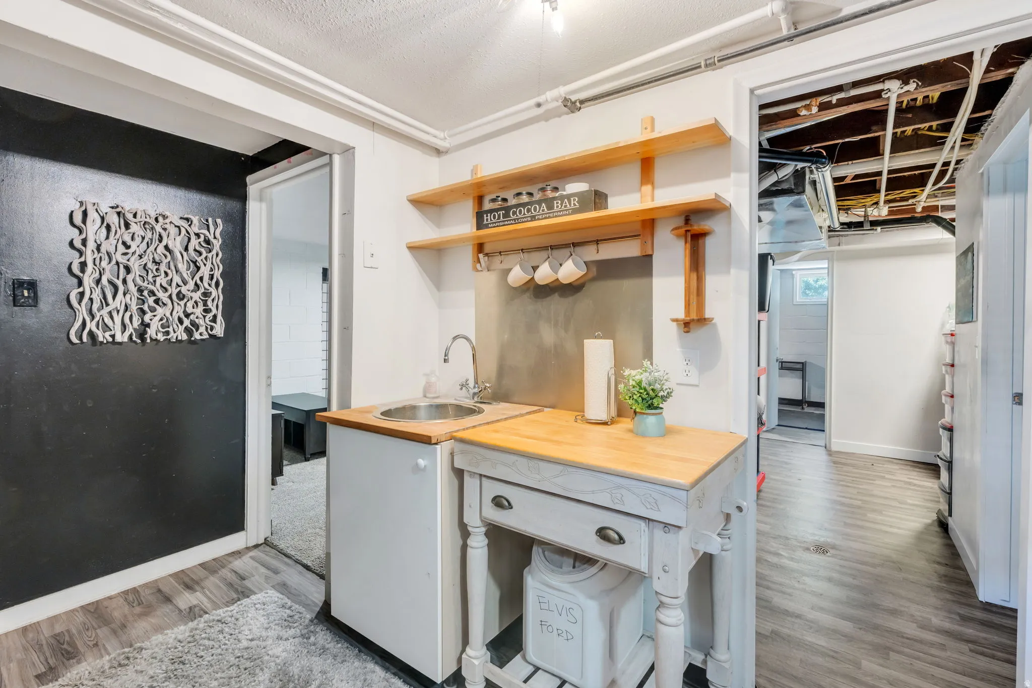 Compact kitchenette featuring a stainless steel sink, wood-finish countertop, and open shelving