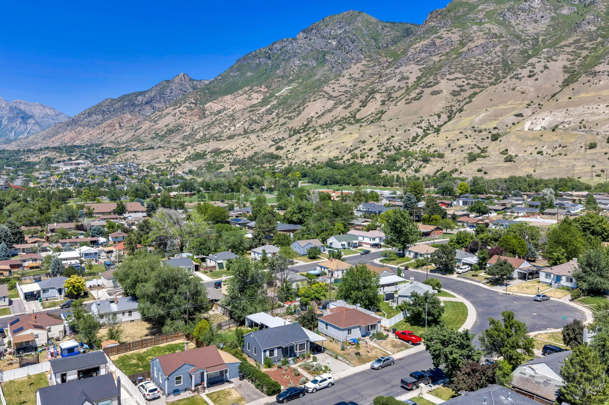 Residential neighborhood featuring a mix of mature trees and established homes, set against a prominent mountain backdrop