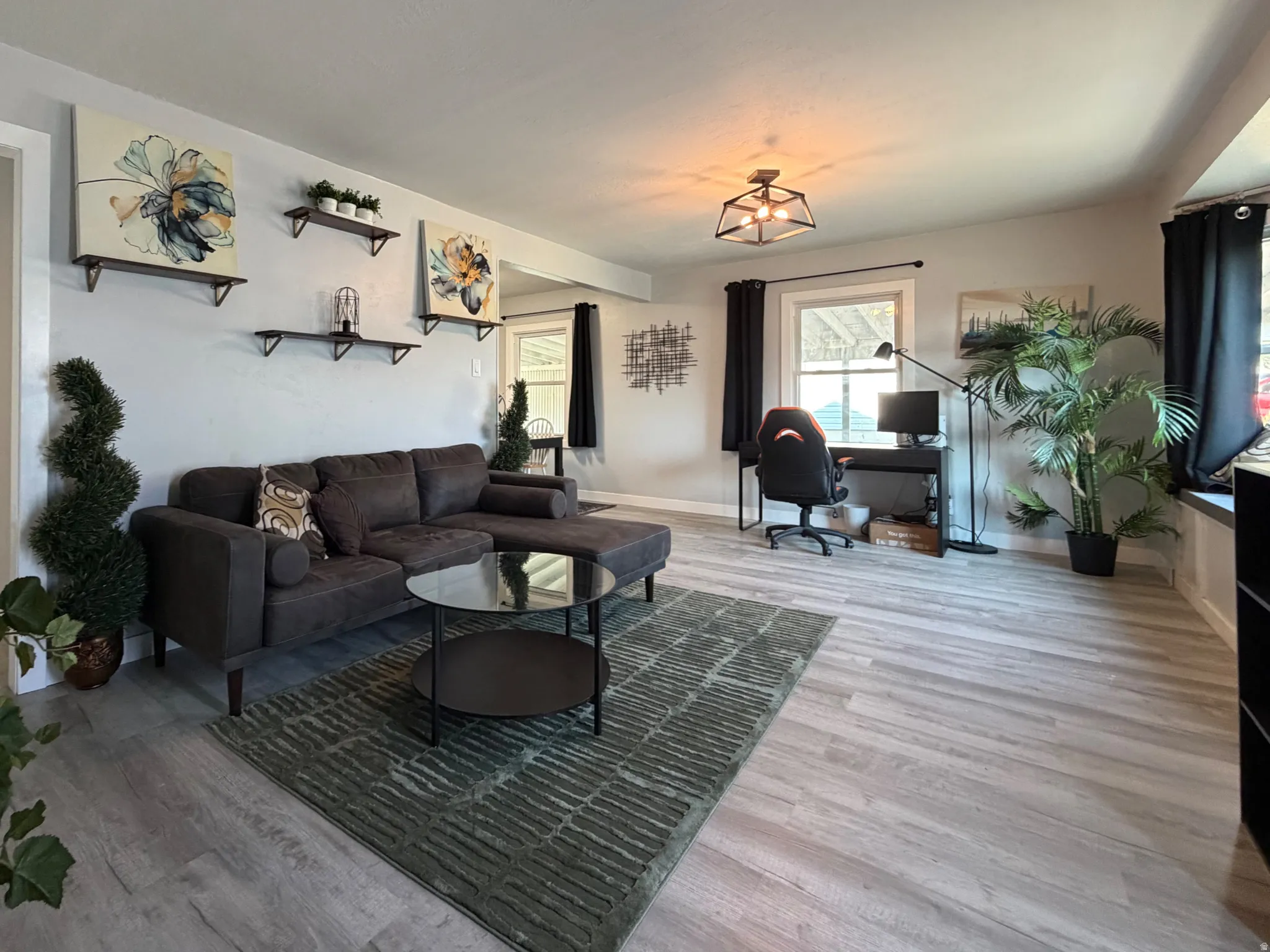 Spacious living area featuring light wood-finish flooring, recessed lighting, and multiple windows.