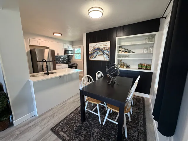 Kitchen featuring a peninsula with a sink and matte black faucet, stainless steel appliances, and a tiled backsplash