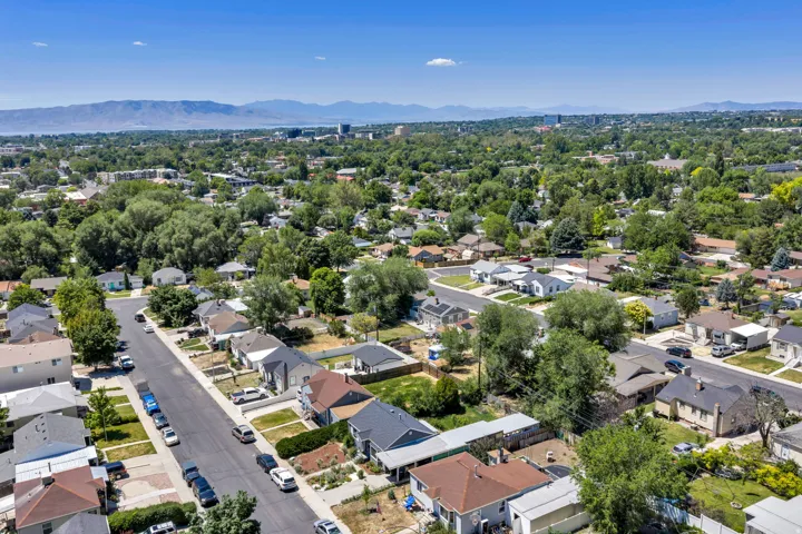 Expansive residential neighborhood featuring mature tree canopy, varied single-family homes, and clear mountain range backdrop