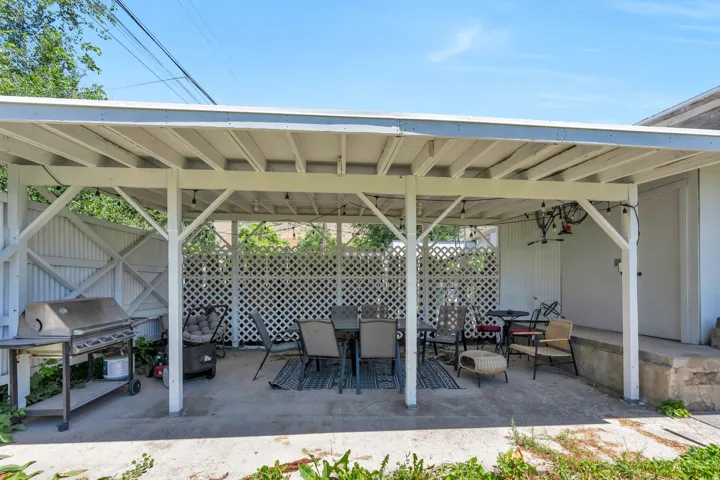 Covered patio with a concrete slab, white lattice privacy screens, and exposed beam ceiling