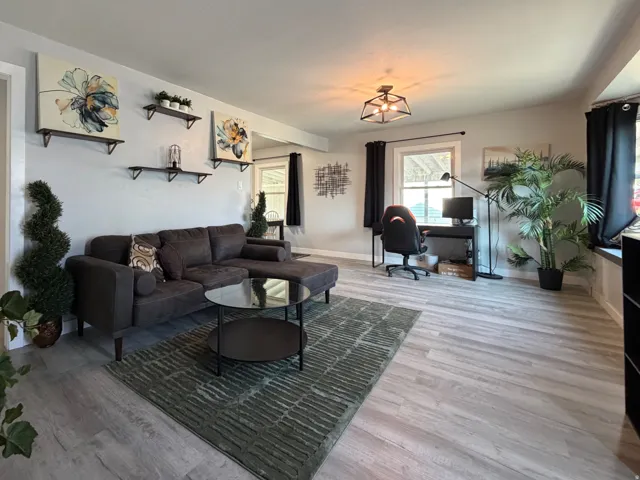 Spacious living area featuring light wood-finish flooring, recessed lighting, and multiple windows.