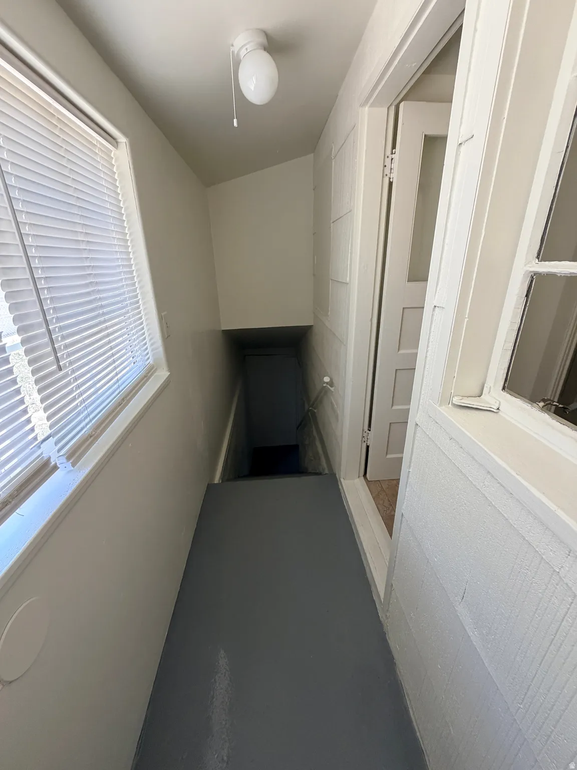Stairwell featuring light gray flooring, white walls, and a window with blinds