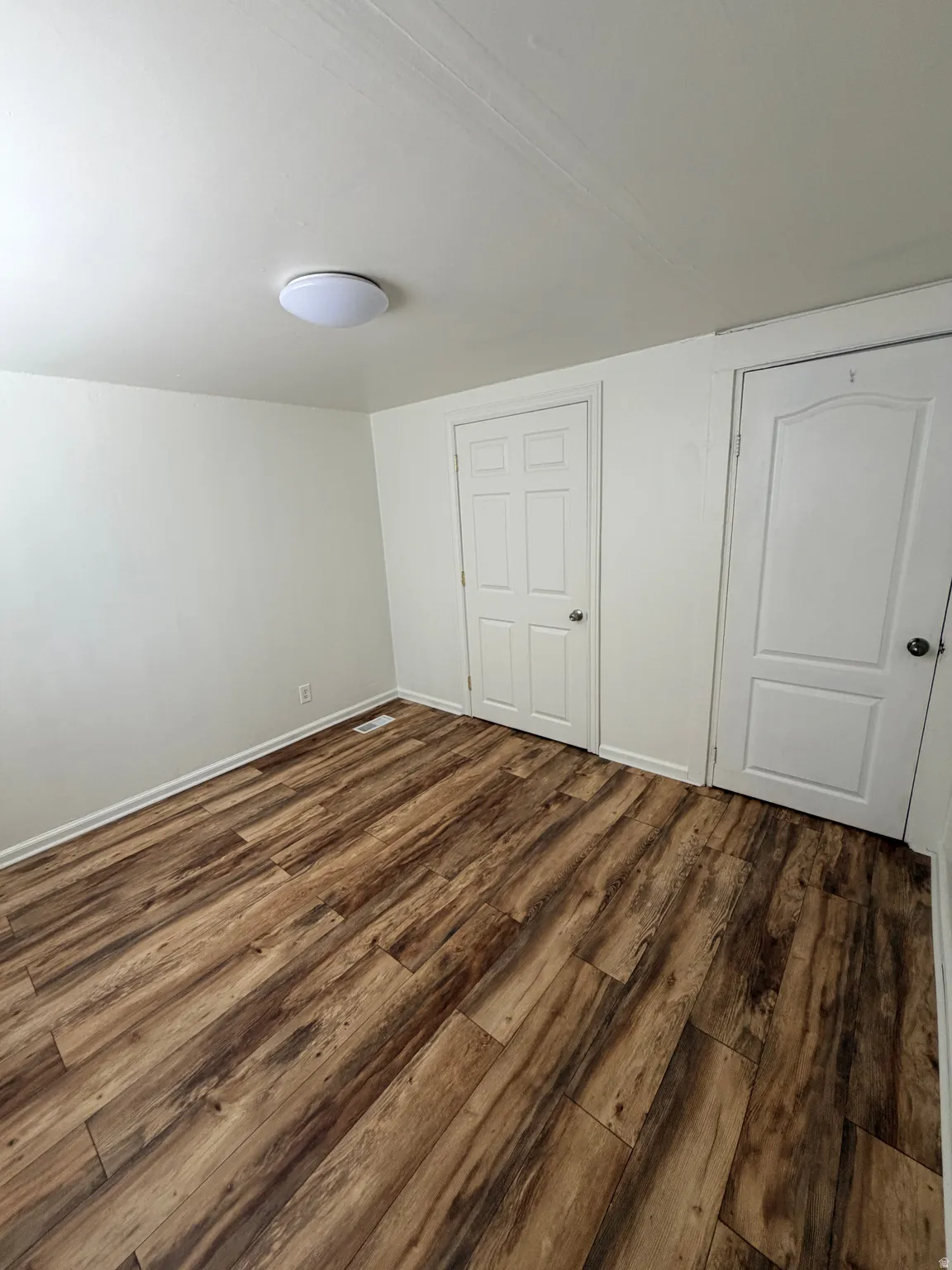 Room featuring wood-finish flooring, white walls, and a flush-mount ceiling light