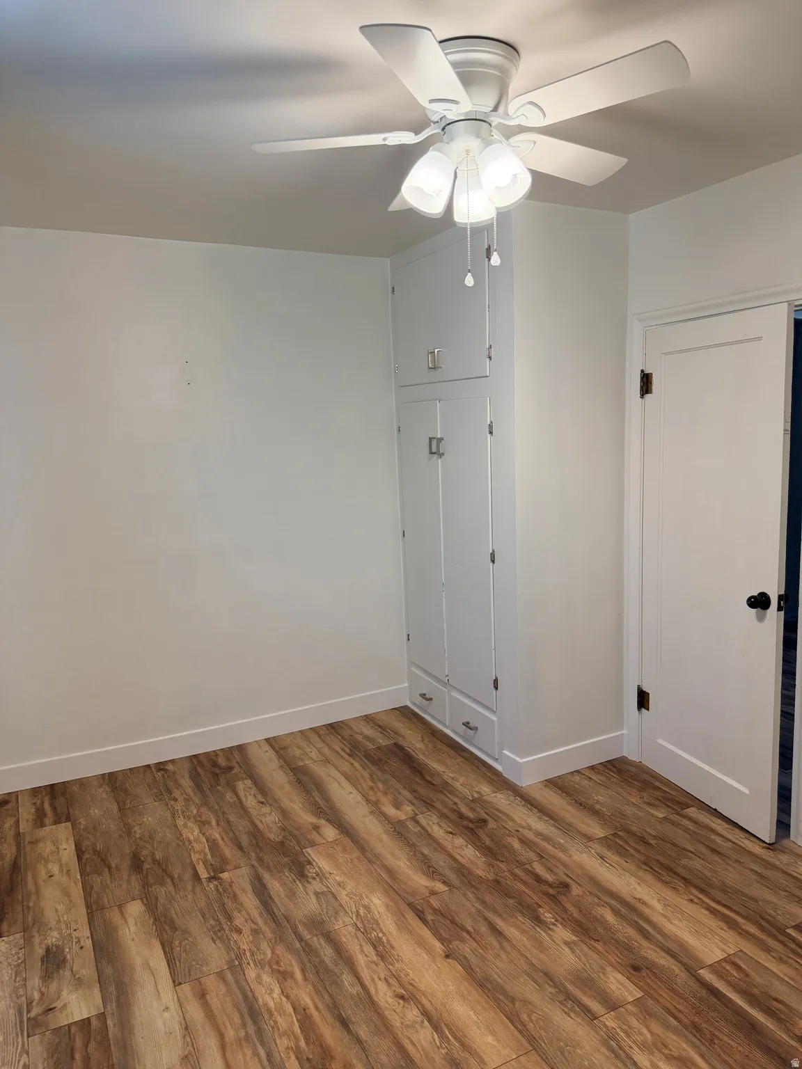 Wood-finish flooring throughout, featuring a white ceiling fan with integrated lighting