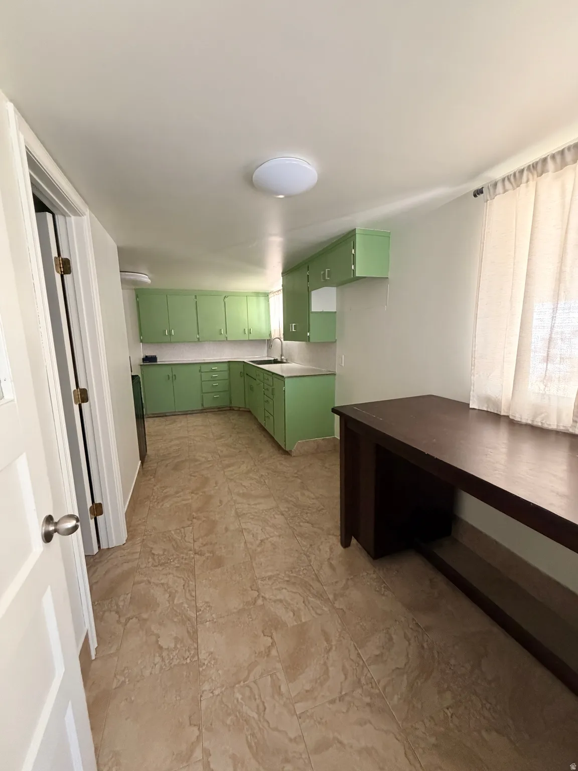 Kitchen featuring green cabinetry, white countertops, a tiled backsplash, and a stainless steel sink with a gooseneck faucet