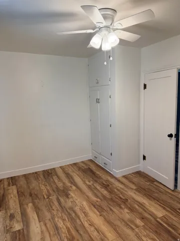 Wood-finish flooring throughout, featuring a white ceiling fan with integrated lighting