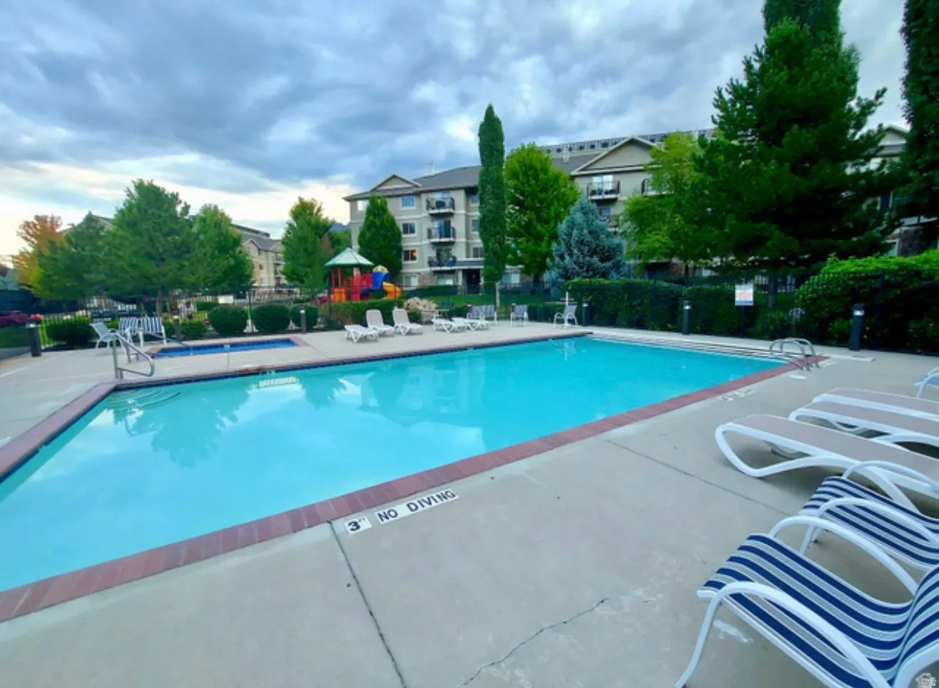 Community swimming pool with an integrated hot tub and surrounding concrete deck