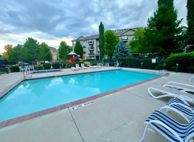 Community swimming pool with an integrated hot tub and surrounding concrete deck