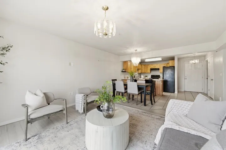 Open-concept living space featuring wood-finish flooring, a contemporary chandelier, and a neutral color palette