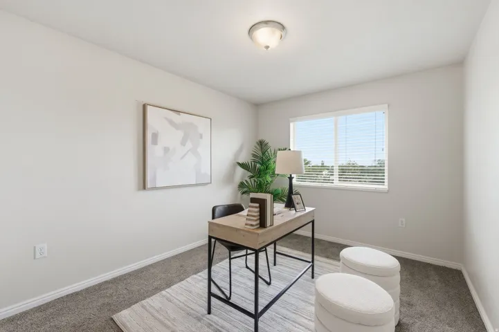 Guest bedroom featuring a single window with horizontal blinds, neutral wall paint, and gray carpet flooring