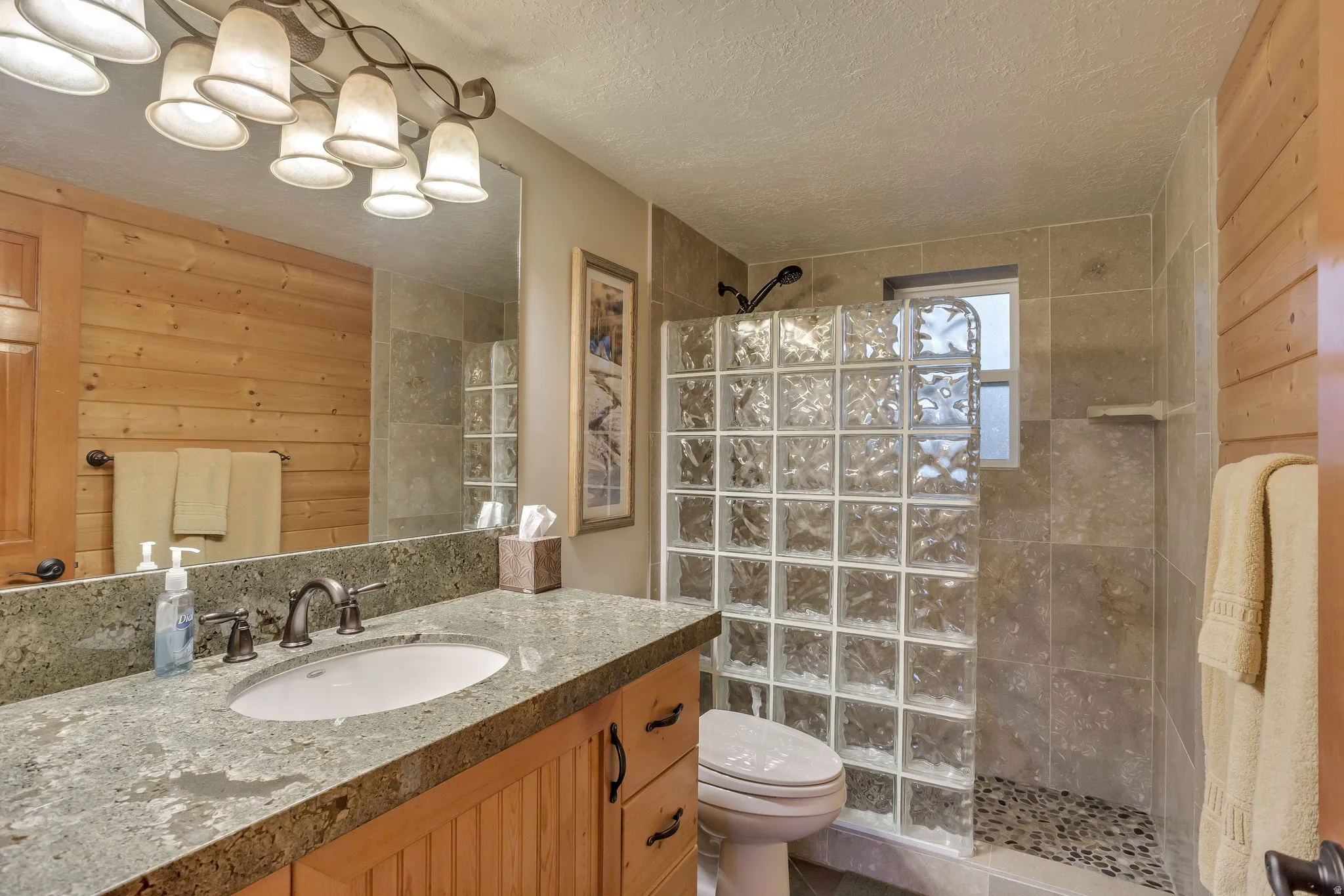 Bathroom featuring a wood-finish vanity with an undermount sink and a speckled countertop