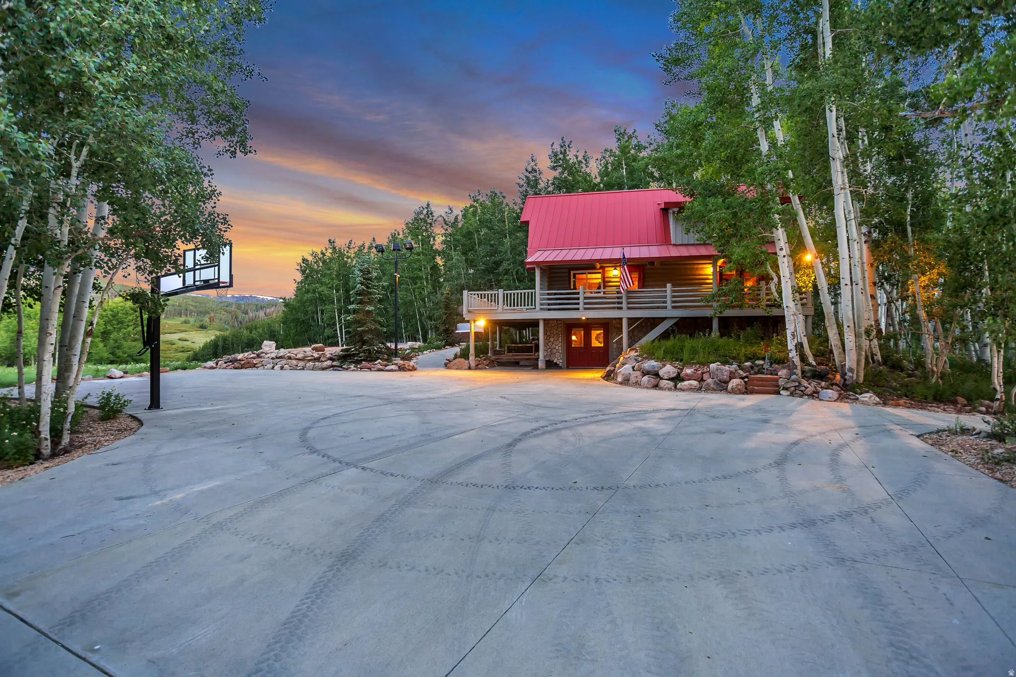 Exterior residence with a red metal roof, surrounded by mature trees