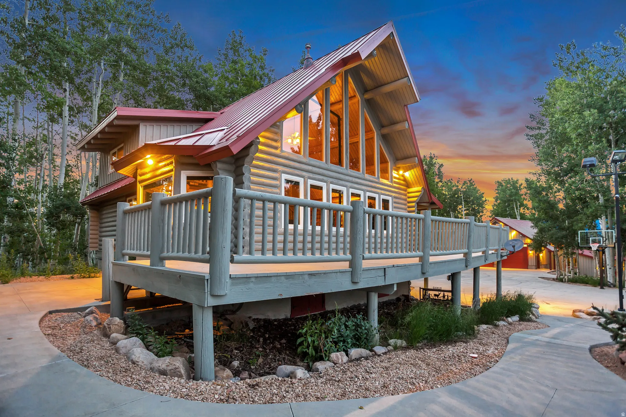 Log cabin exterior featuring a red metal roof, a full-length deck, and a large window wall
