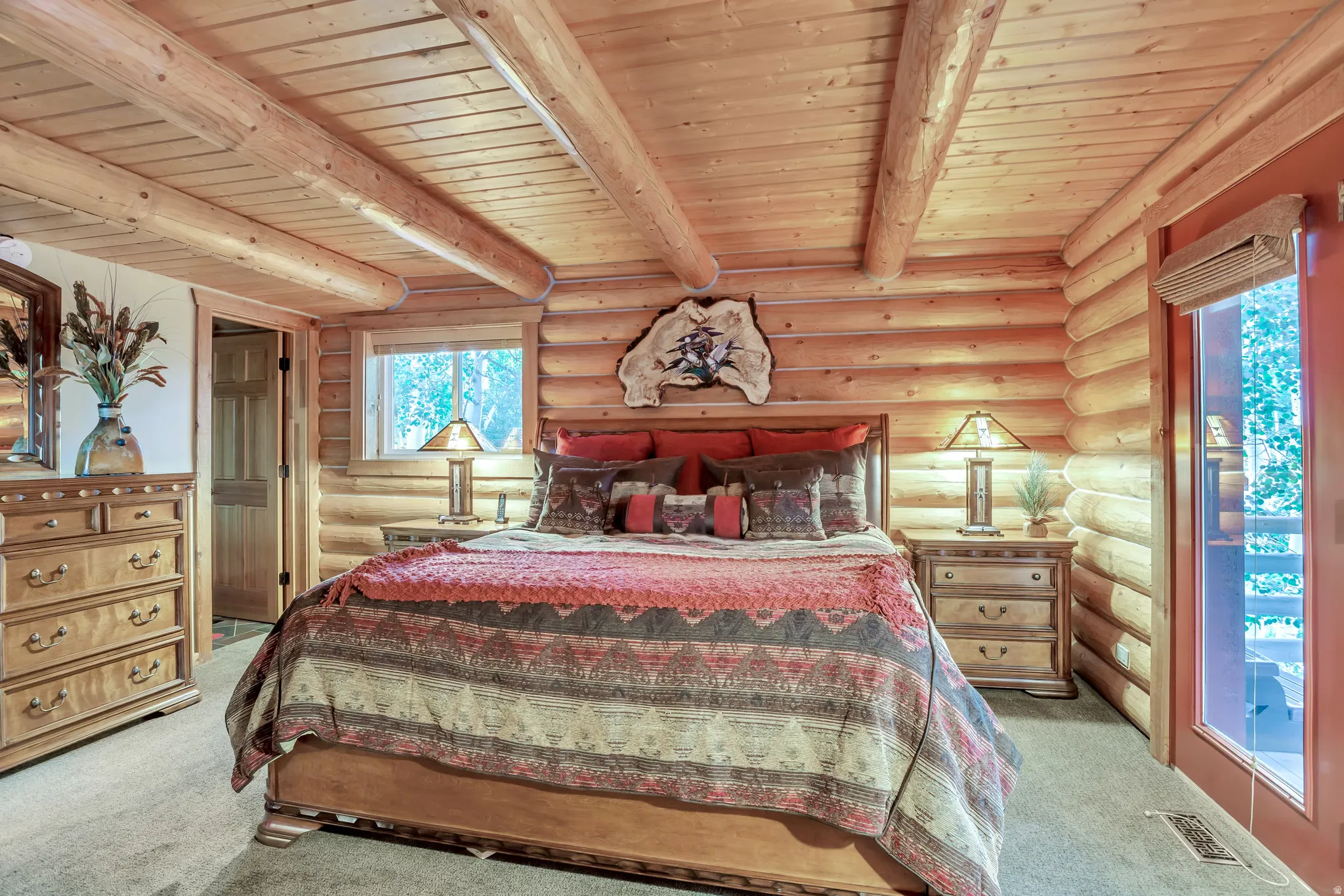 Wood-paneled bedroom featuring exposed wood ceiling beams, a window, and a glass-paneled door