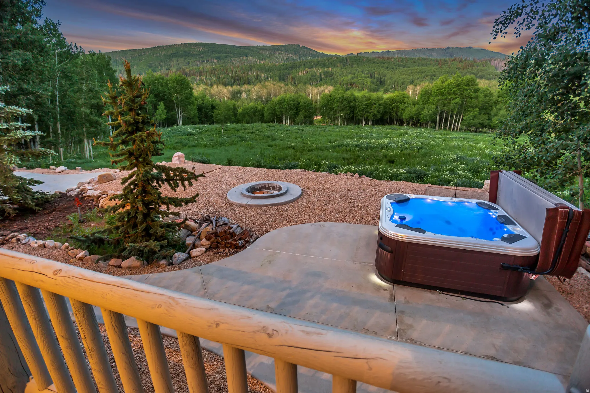 Outdoor patio featuring a hot tub, a built-in fire pit, and a natural wood railing