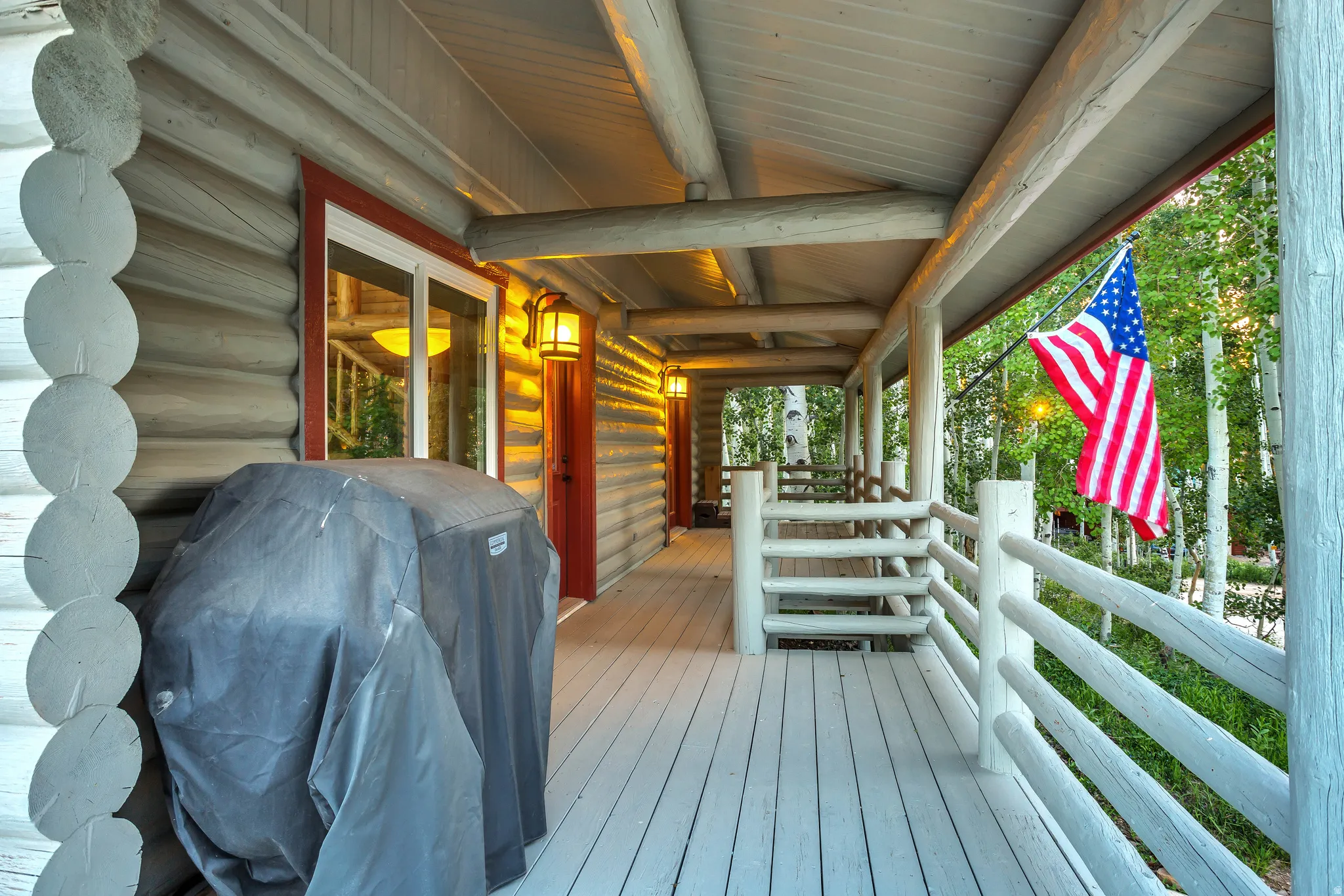 Expansive log cabin porch featuring a wood-finish deck, log railings, and matching log posts
