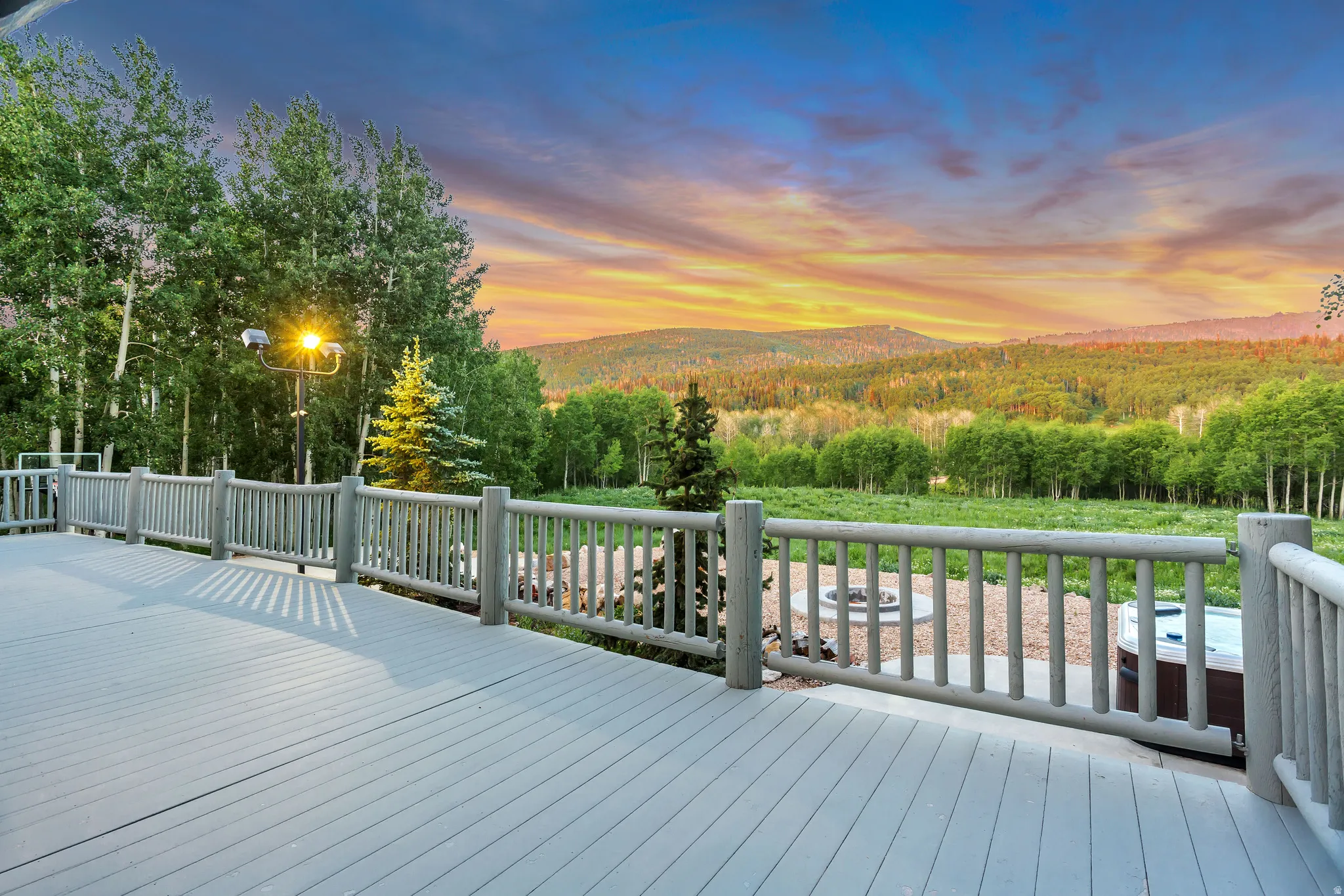 Expansive outdoor deck featuring a hot tub, a built-in fire pit area, and log-style railings