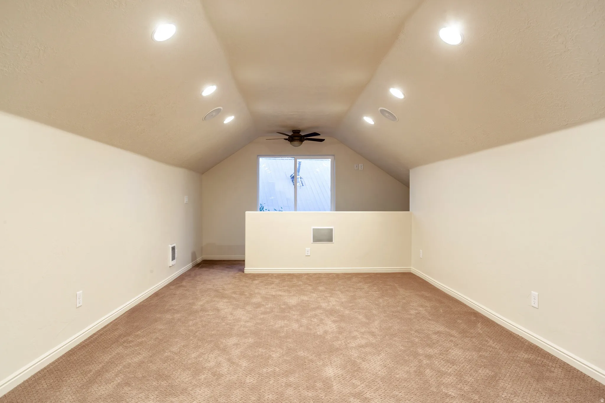 Spacious room featuring vaulted ceilings, recessed lighting, and a ceiling fan