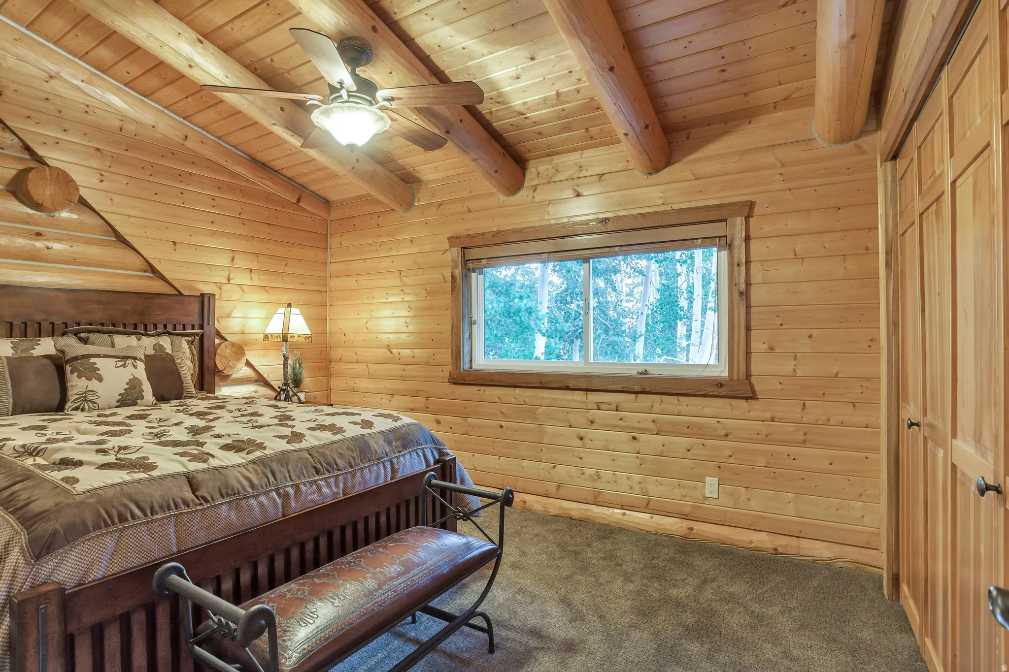Wood-paneled interior featuring a vaulted ceiling with exposed log beams