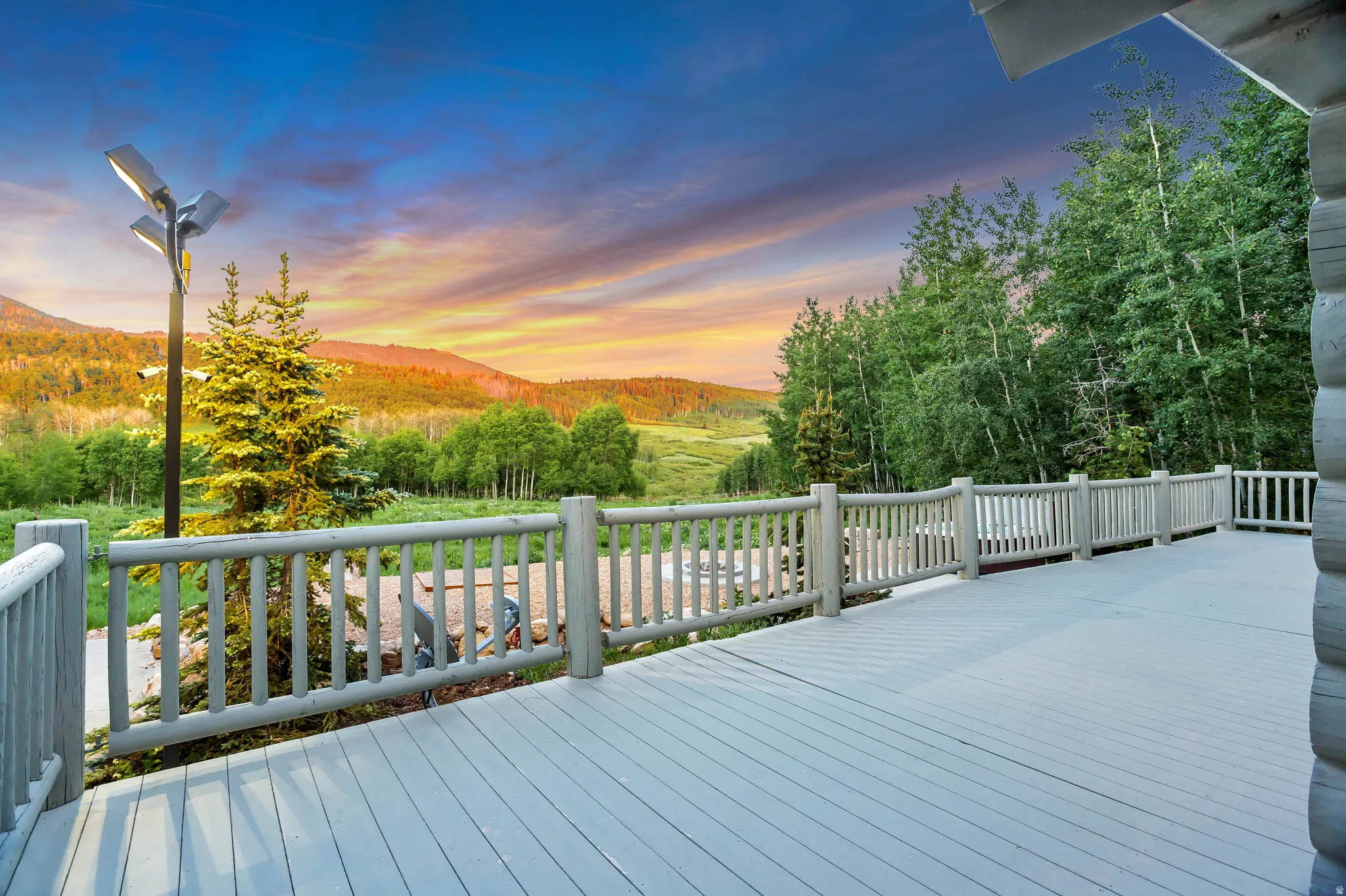 Expansive outdoor deck featuring composite decking, log railing, and a multi-fixture outdoor light post