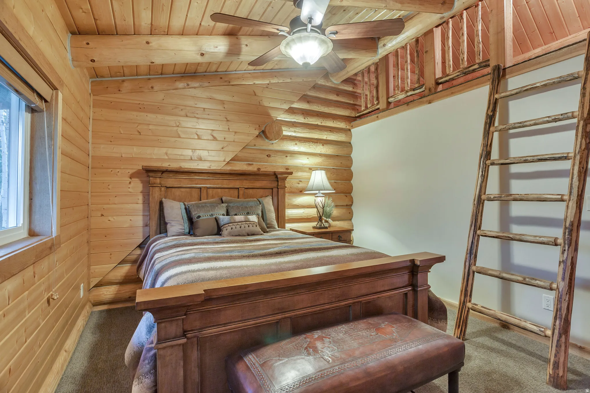 Bedroom featuring wood-paneled walls and ceiling, a rustic wood ladder, and a ceiling fan with integrated lighting