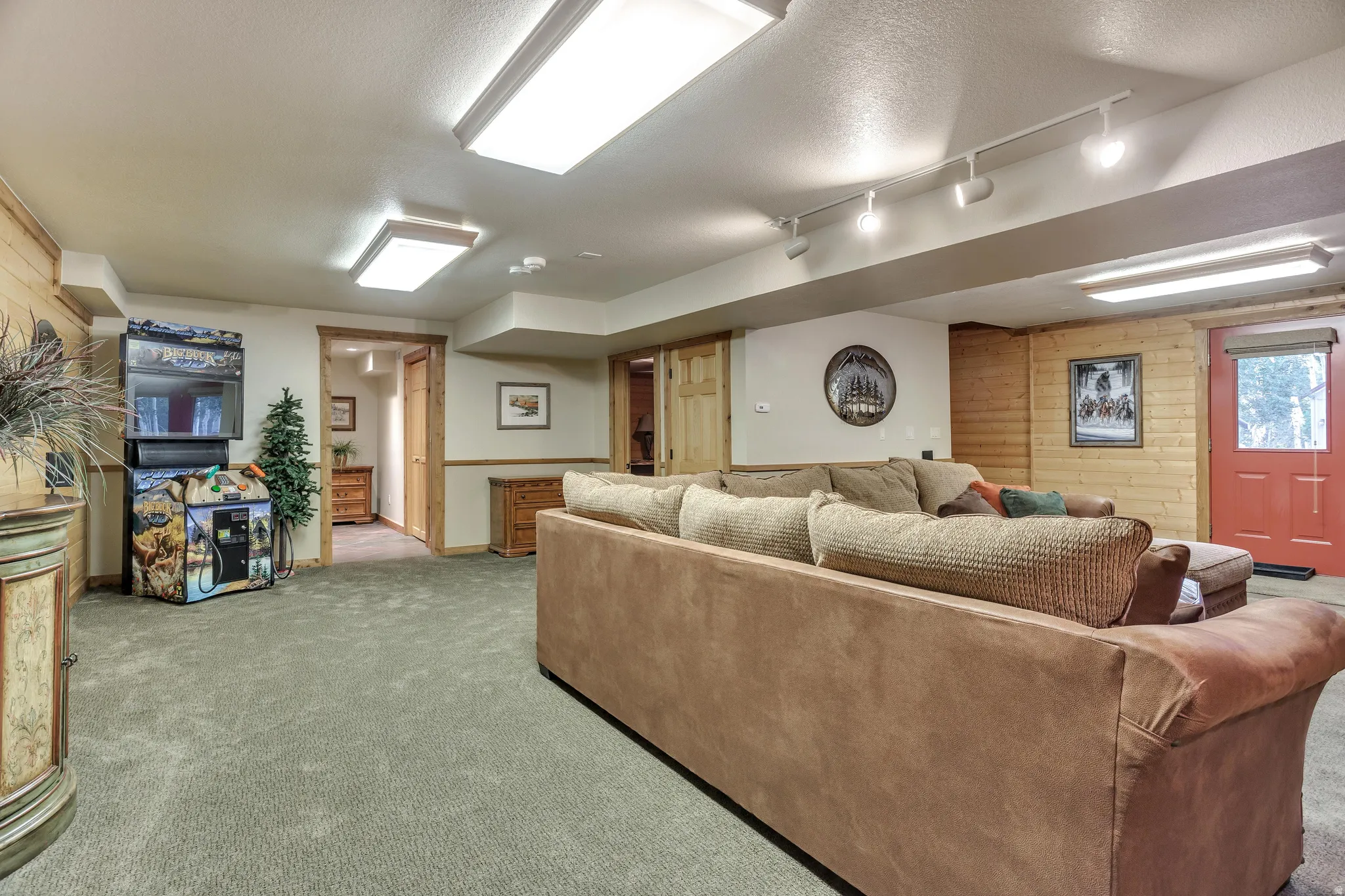 Finished lower level featuring recessed lighting, track lighting, wood paneling, and a red exterior door