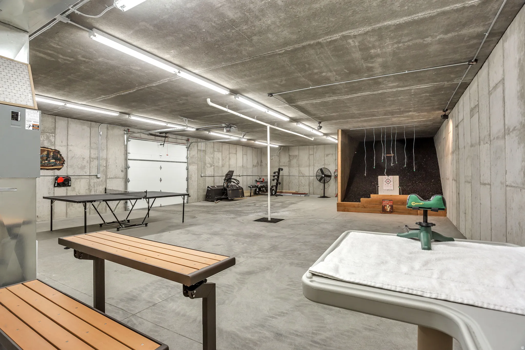 Spacious concrete-walled basement featuring exposed concrete ceilings and ample fluorescent lighting