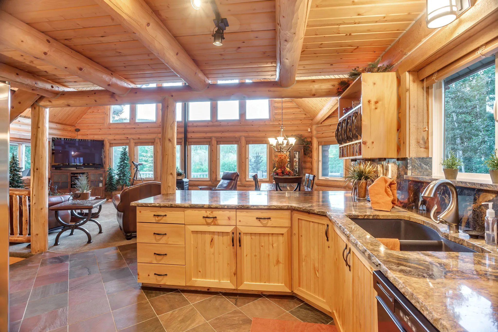 Open-concept kitchen featuring wood cabinetry, stone countertops, and a dual-basin sink