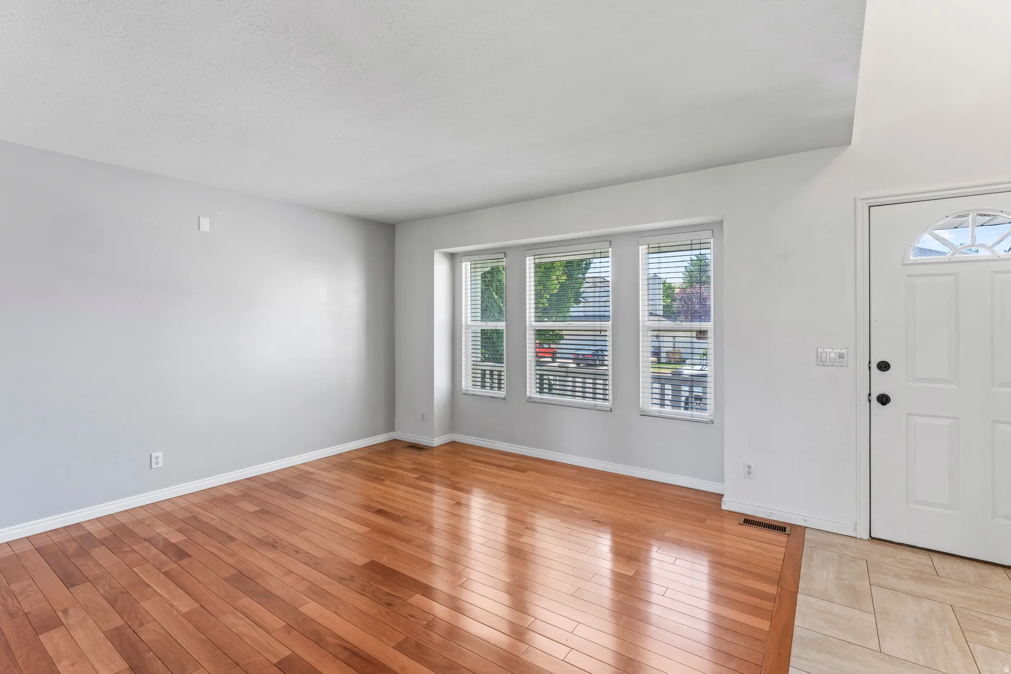 Entryway featuring hardwood-finish flooring, light gray walls, white trim, and a white paneled door with an arched glass insert