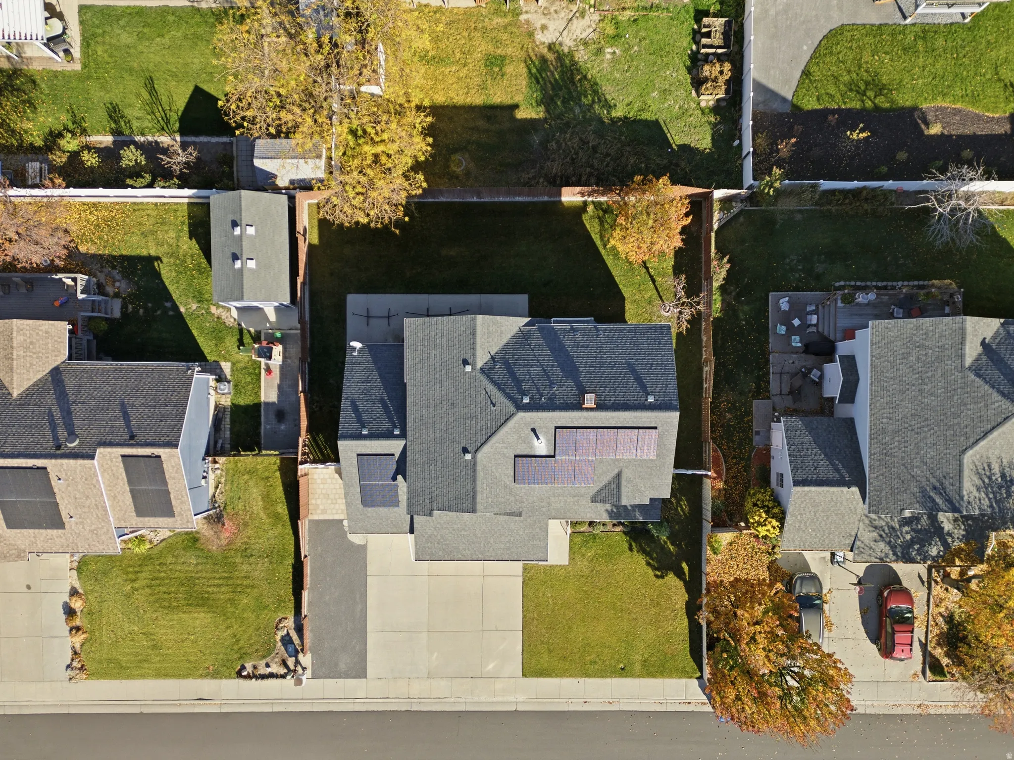 Property featuring a dark shingle roof with solar panels, a concrete driveway, and a manicured lawn