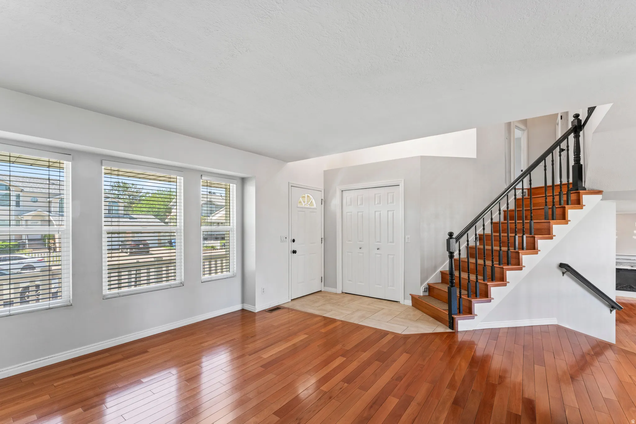 Open living area featuring wood-finish flooring and a staircase with a black wrought iron railing