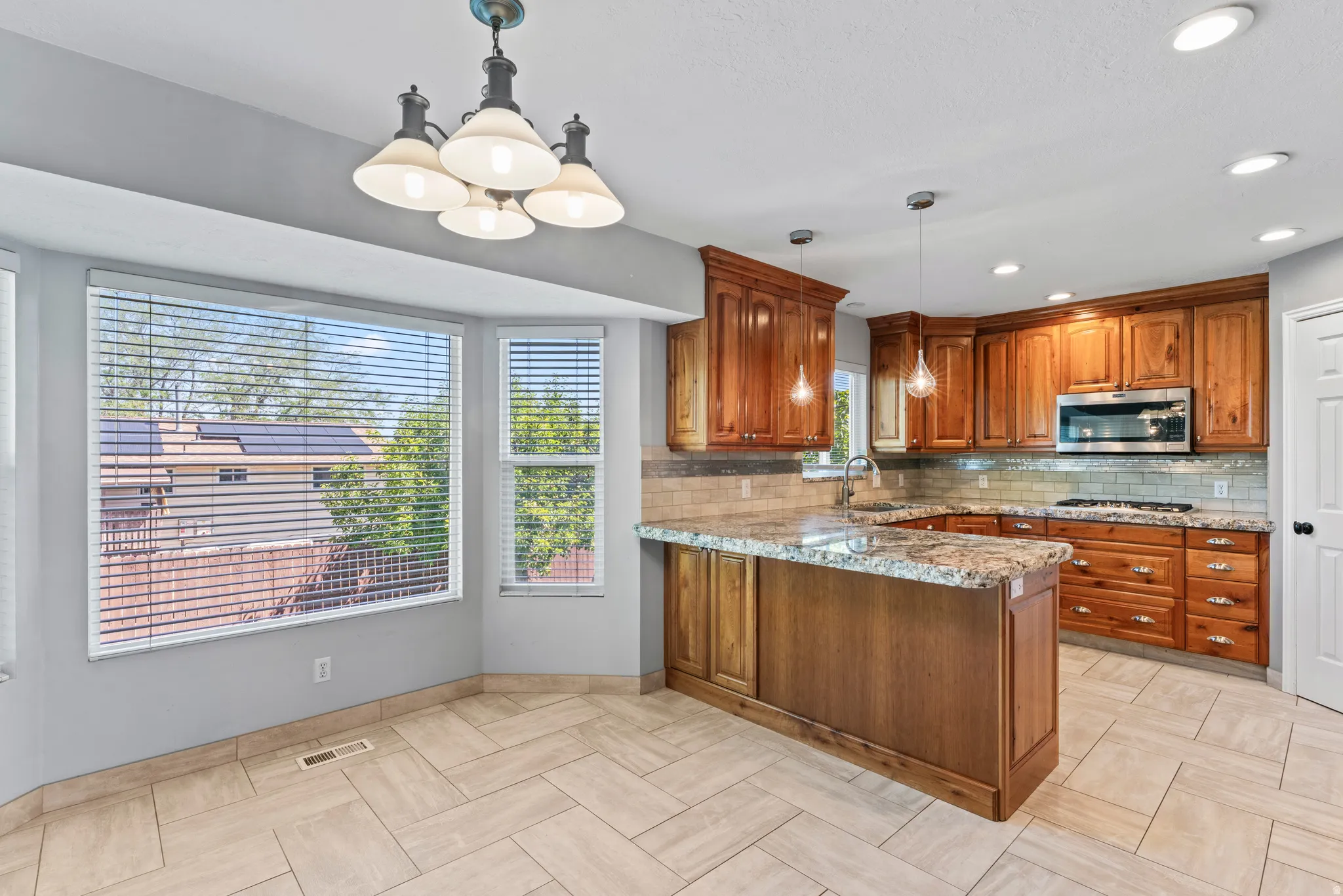 Kitchen featuring wood cabinetry, granite countertops, stainless steel appliances, and a tiled backsplash