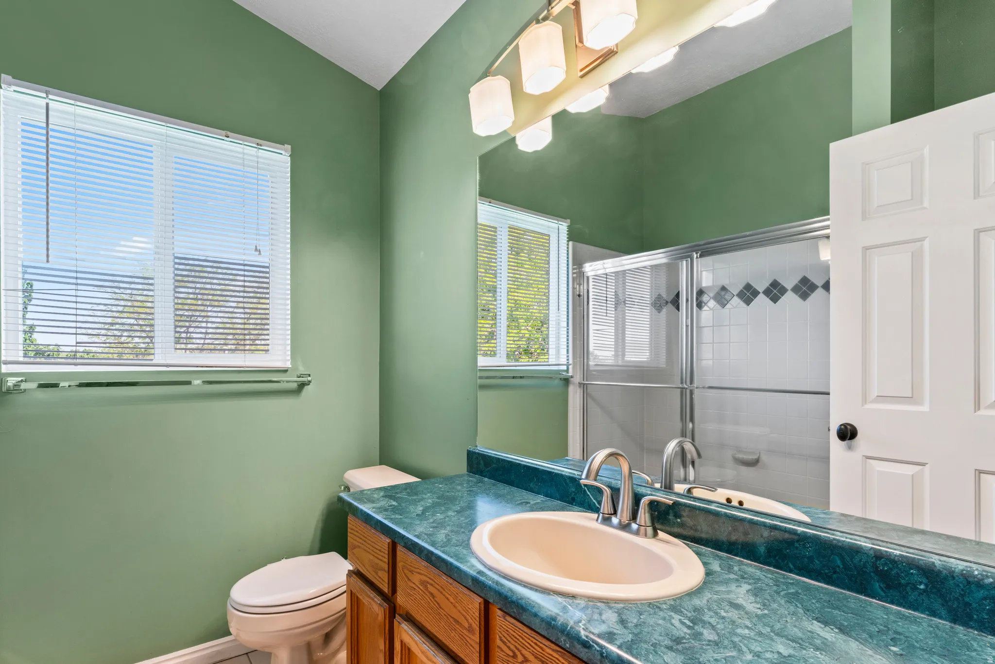 Bathroom featuring a single vanity with a round basin, a patterned countertop, and a wood-finish cabinet